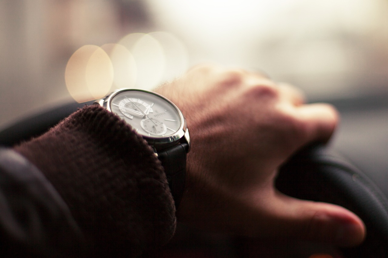 A person's hand on a steering wheel and their wrist watch
